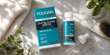 대리석 표면의 헤어브러시 옆에 놓인 FOLIGAIN DHT 세럼 상자, 병 및 스포이트.
