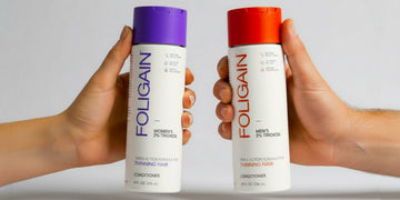보라색과 주황색 뚜껑이 달린 FOLIGAIN 여성용 및 남성용 TRIOXIDIL 컨디셔너를 들고 있는 두 손.