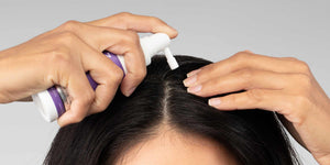 머리카락을 가르며 FOLIGAIN 외용 트리트먼트를 두피에 바르는 여성
